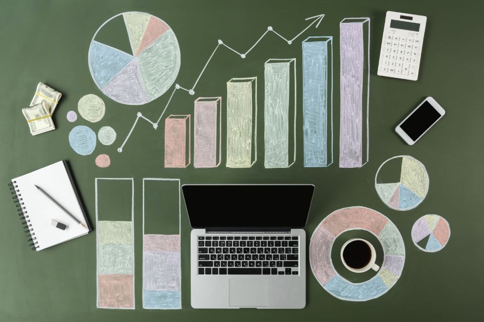 Graphs drawn in chalk next to a laptop, pad of paper, calculator, and cell phone.