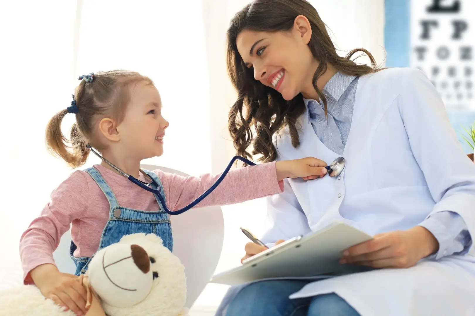 Little girl at the doctor for a checkup auscultates the heartbeat of the doctor.