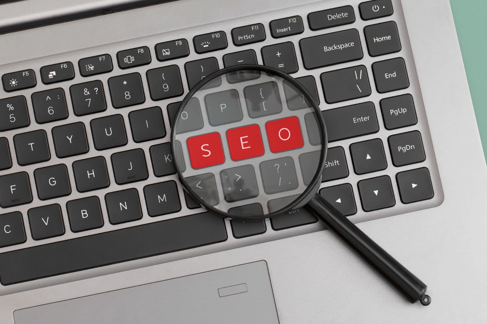 Word “SEO” on a laptop keyword with a magnifying glass.