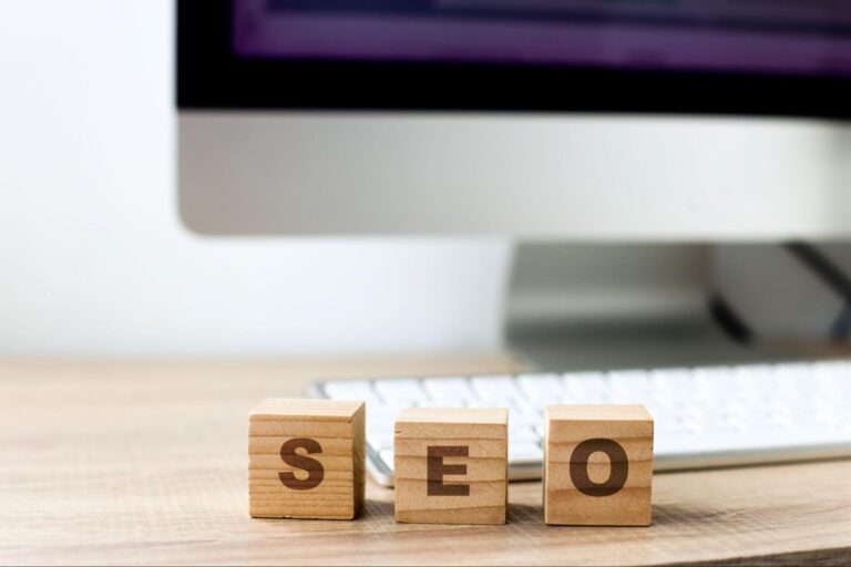 Wooden blocks that spell out “SEO” in front of a desktop computer.