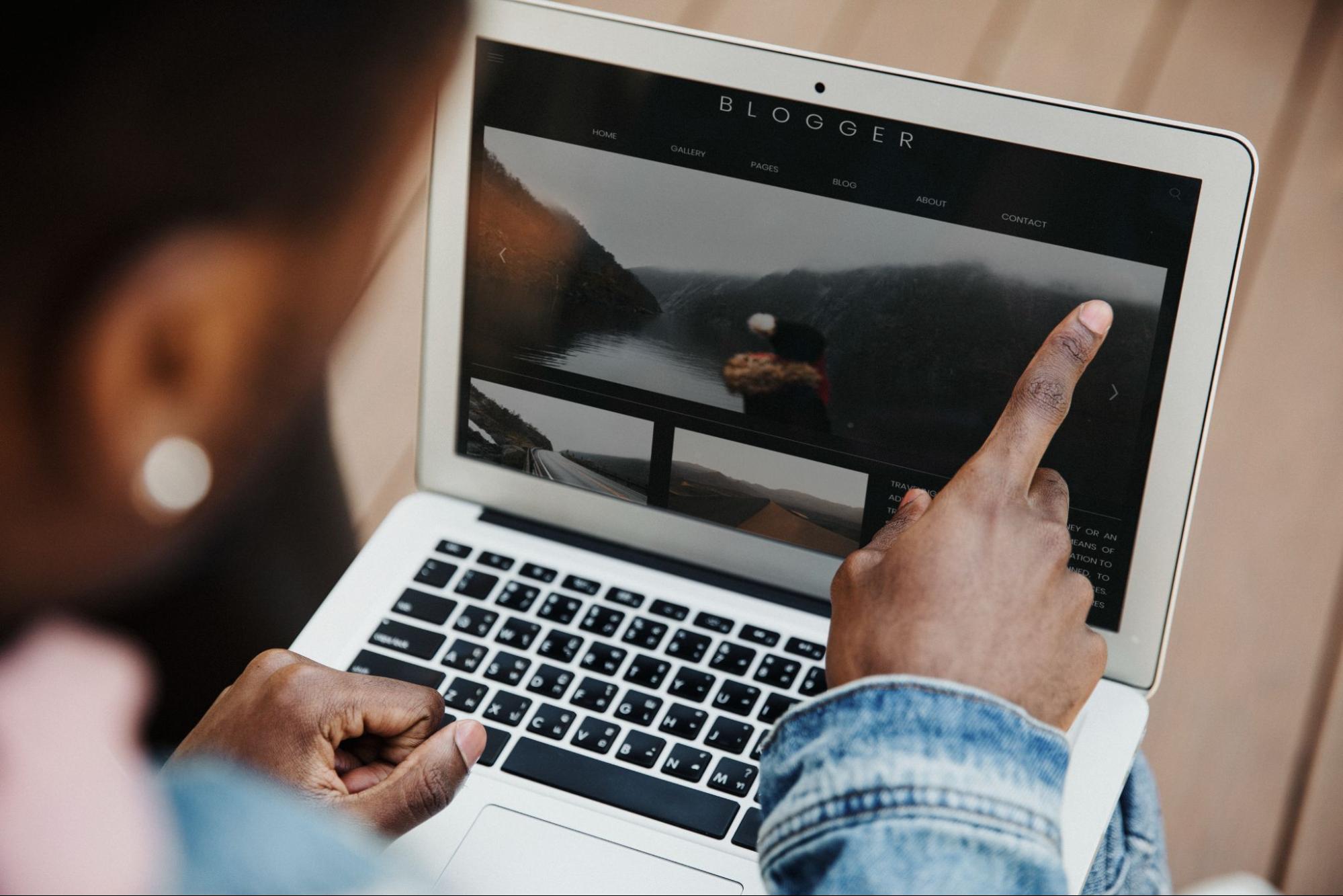 Person pointing at their laptop screen.