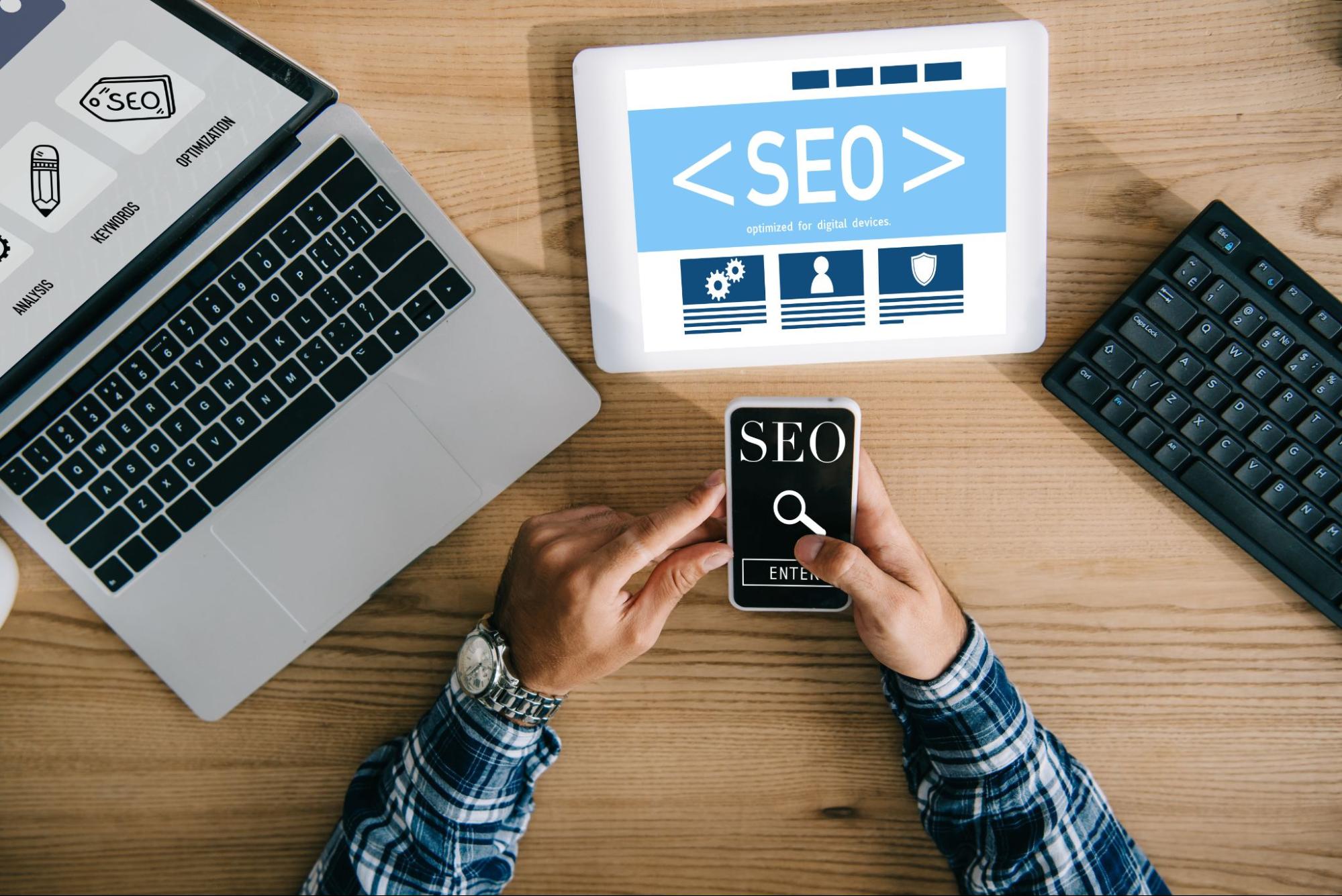 Man using a phone and tablet that have the words “SEO” on the screen.