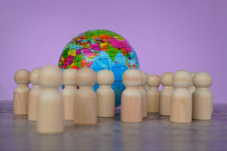 Wooden models of people next to a globe.