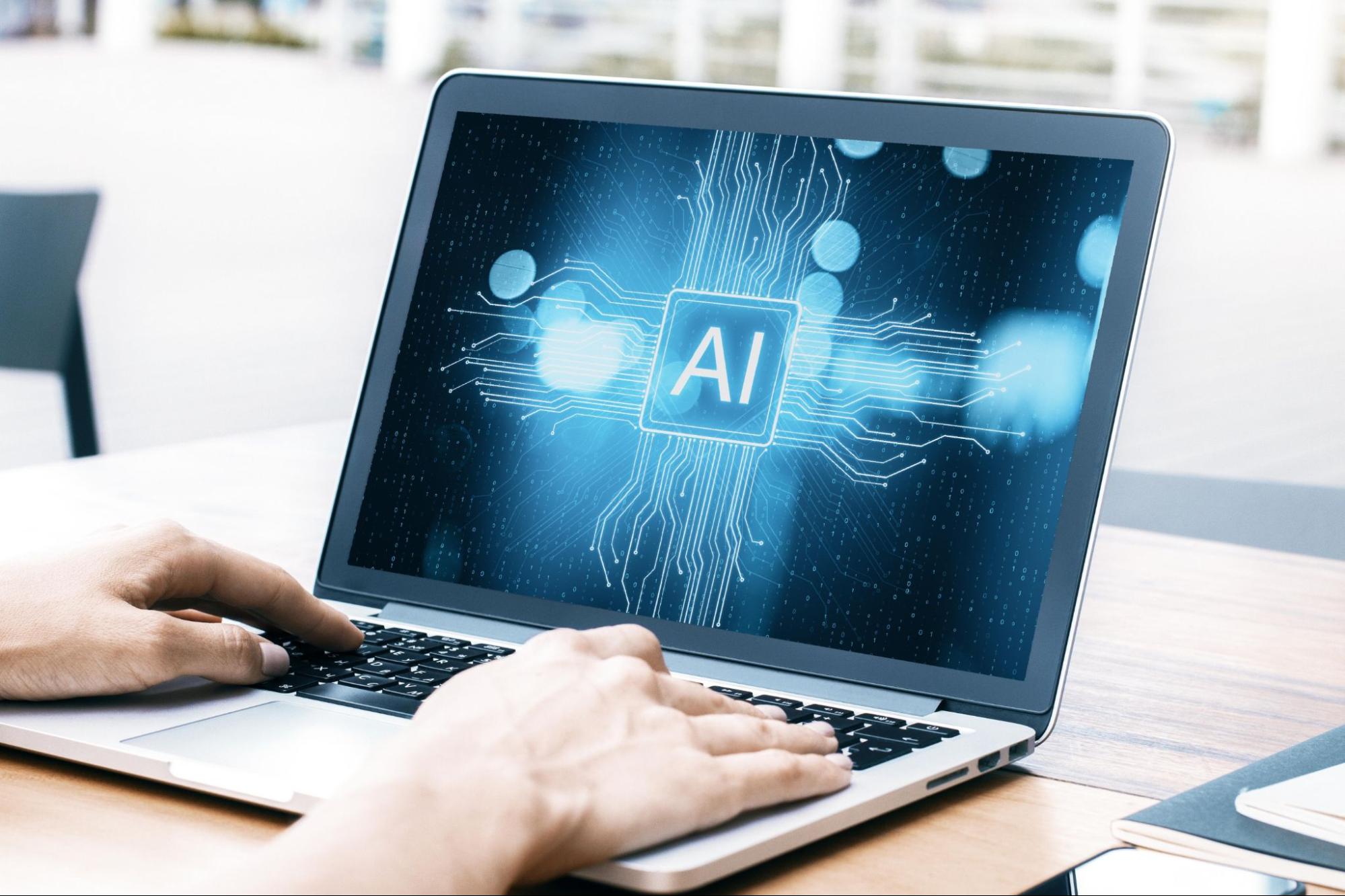 Word “AI” on a computer screen with someone typing.